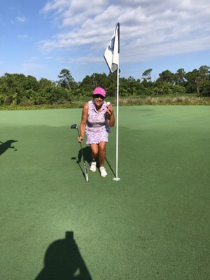 harbour ridge member woman holding golf ball at hole and smiling at first hole-in-one