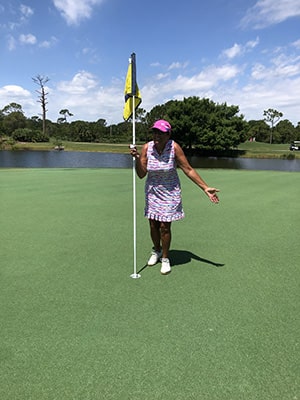 harbour ridge member woman holding golf ball at hole and smiling at second hole-in-one